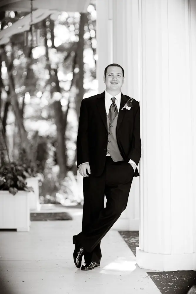 groom formal formal shot of groom leaning against a pillar