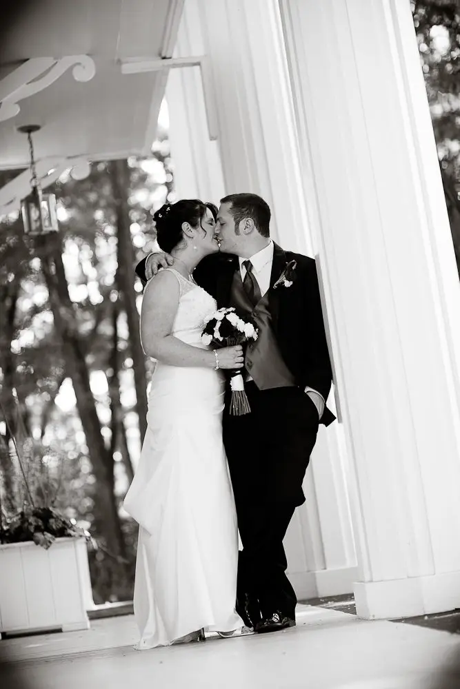 bride and groom kissing couple kissing during formals leaning on a pillar