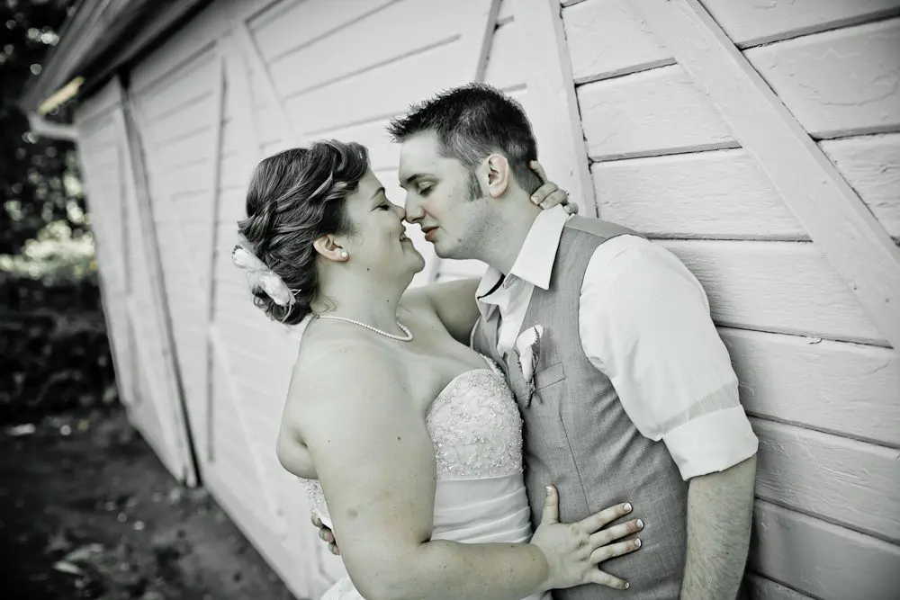 couple leaned up against barn bride and groom looking into each other's eyes