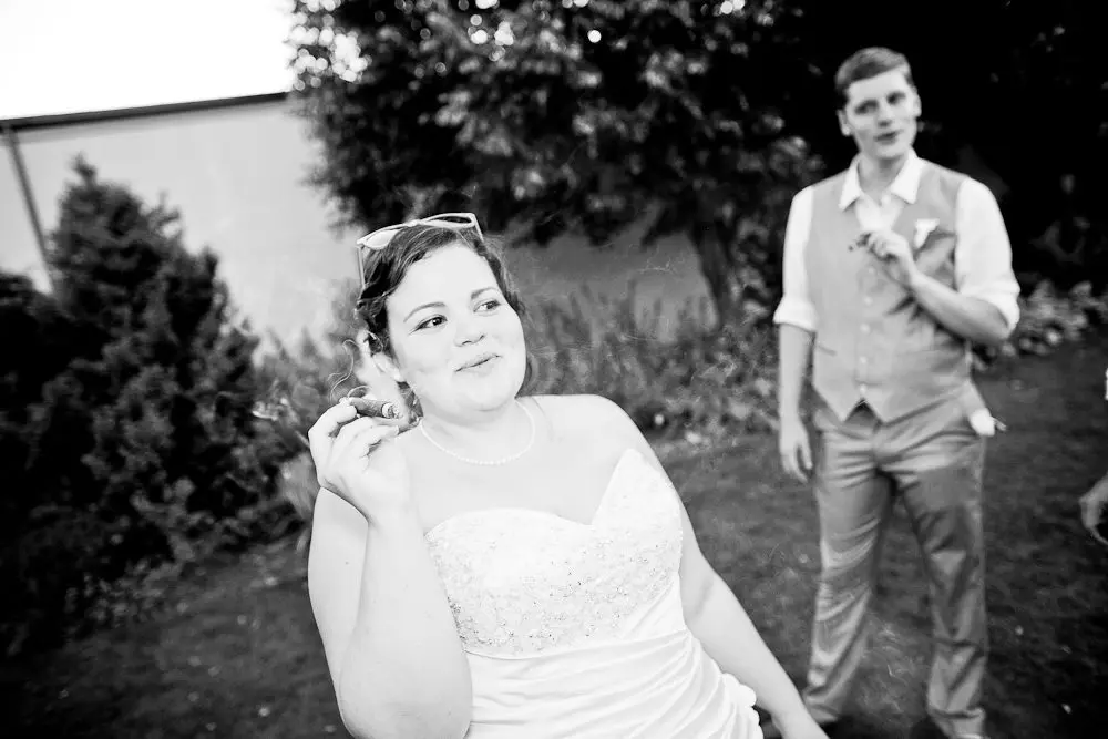 bride smoking a cigar bride hanging out with the groomsmen