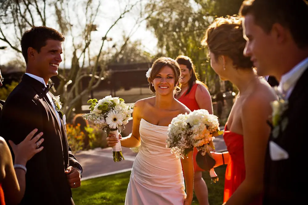 bride smiling bride being greeted by the wedding party after the ceremony