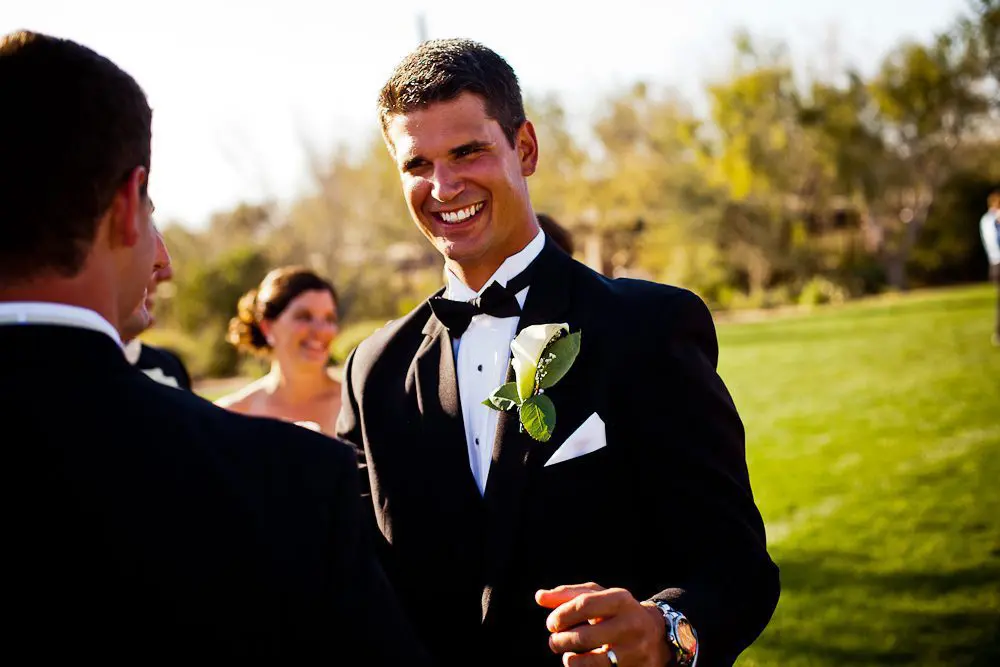 groom smiling groom being greeted by the wedding party after ceremony