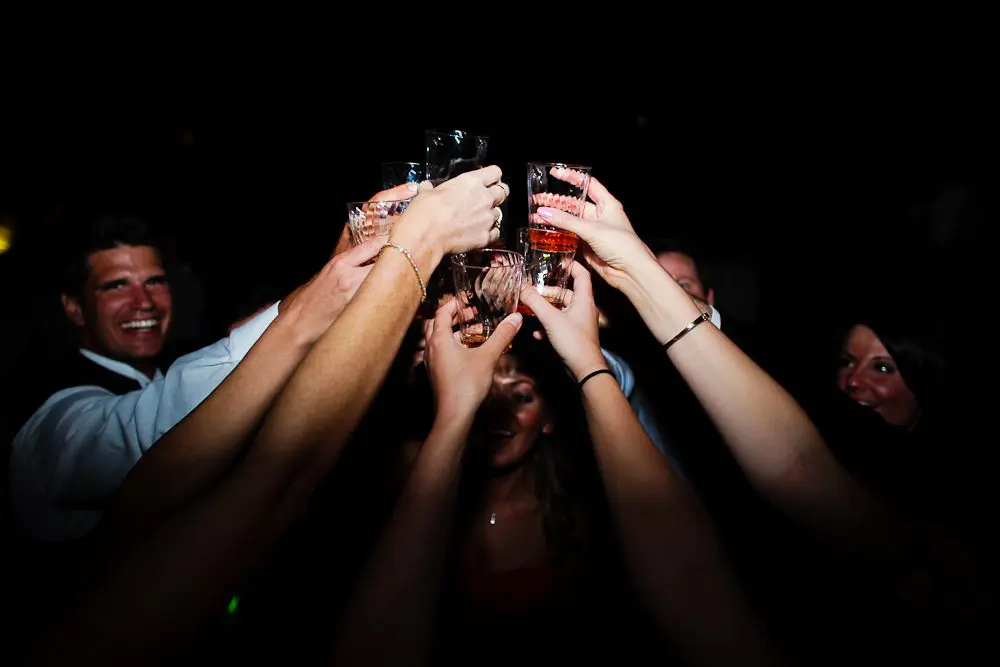 groom smiling during a group toast fun pic of everyone taking shots at the reception
