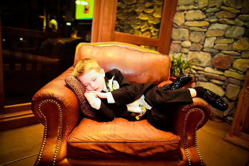 the ring bearer the ring bearer asleep on a chair during the wedding reception