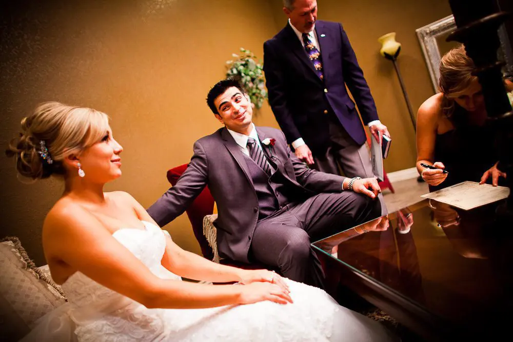 the groom giving the bride a funny face while signing the marriage certificate