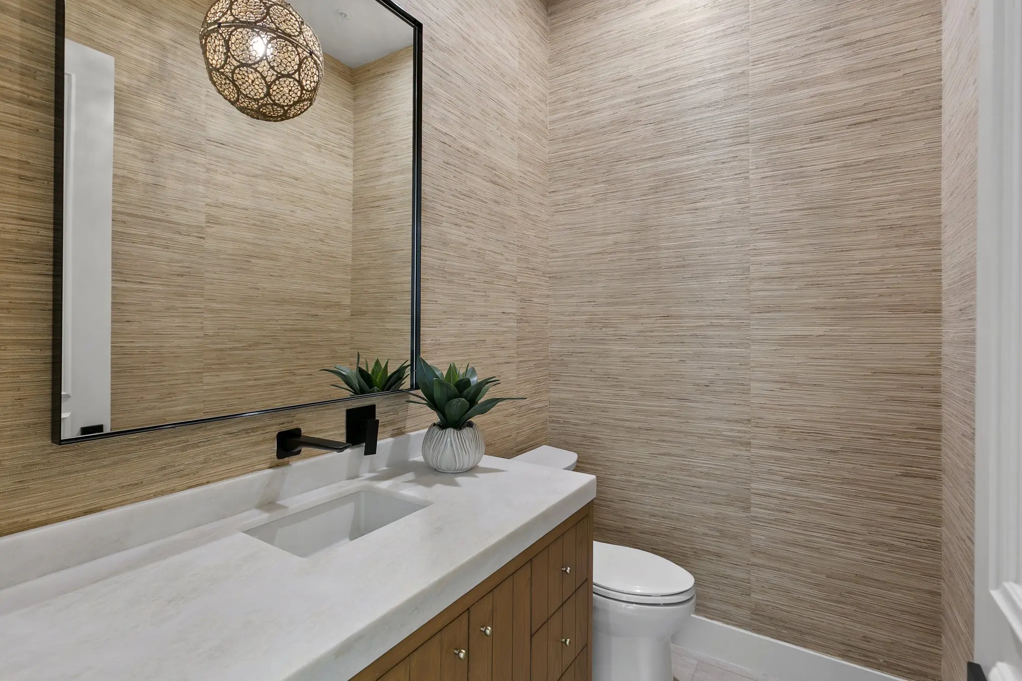Powder room with grasscloth wall and black-framed mirror
