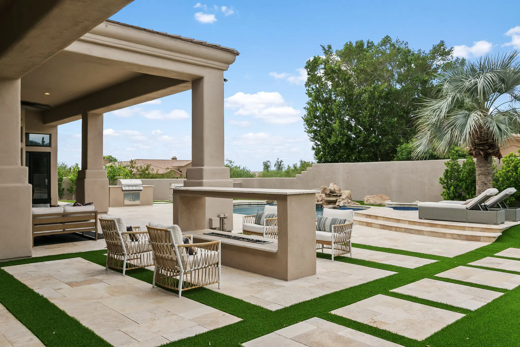 Outdoor fireplace and seating on travertine and turf, Scottsdale backyard