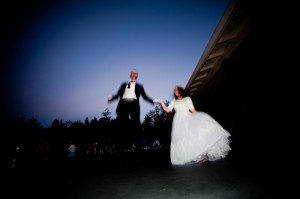 bride and groom jumping on trampoline at backyard wedding