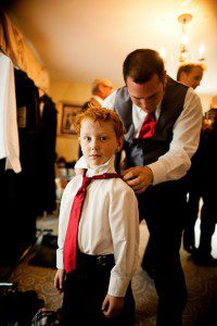 ring bearer getting his tie put on by the groom