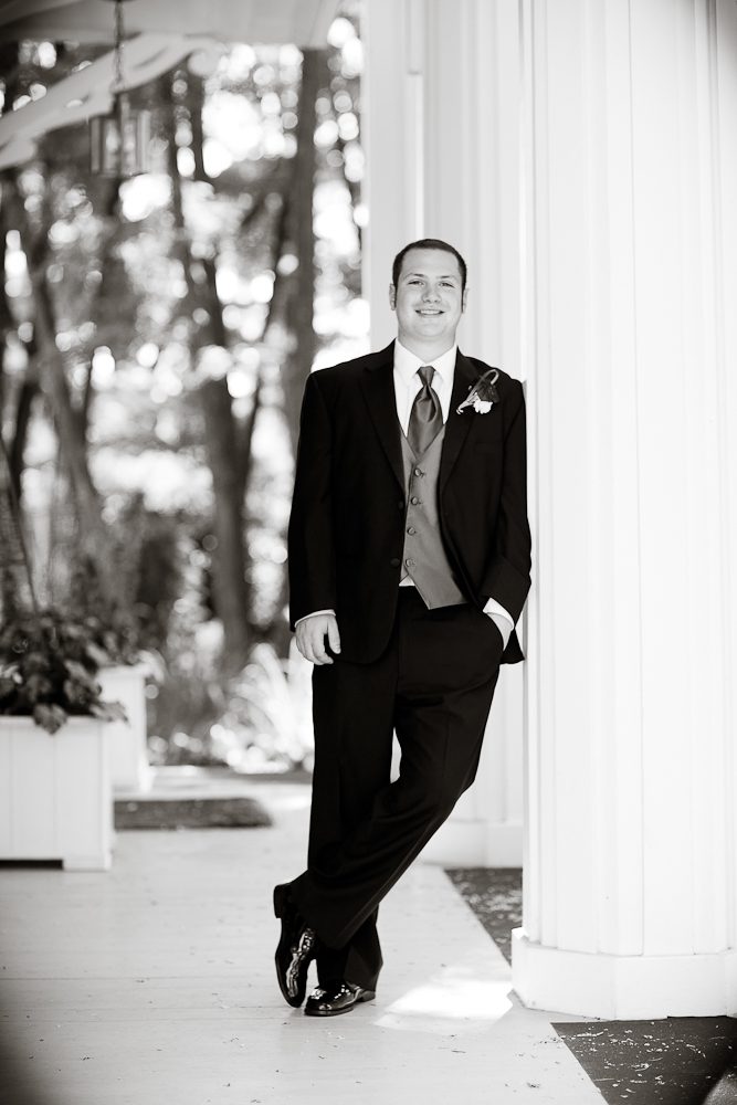 formal shot of groom leaning against a pillar