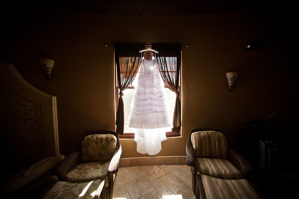 back lit shot of wedding dress hanging in front of the window