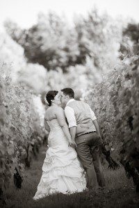 couple kissing while walking down a vineyard row