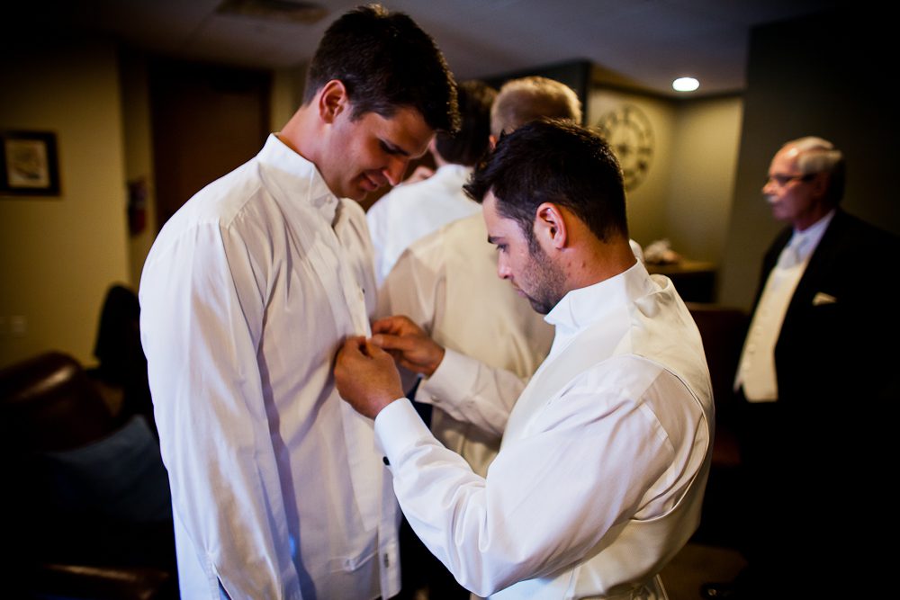 The Groom getting little help with buttons on his shirt