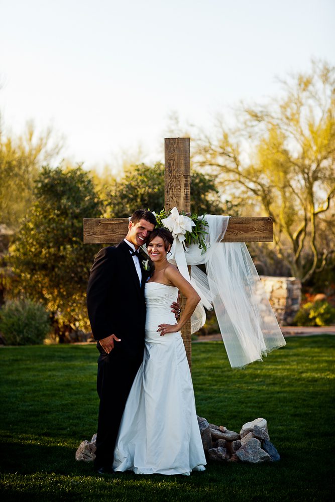 bride and groom in front of cross