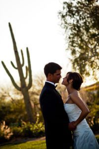 bride and groom kissing with cactus in background