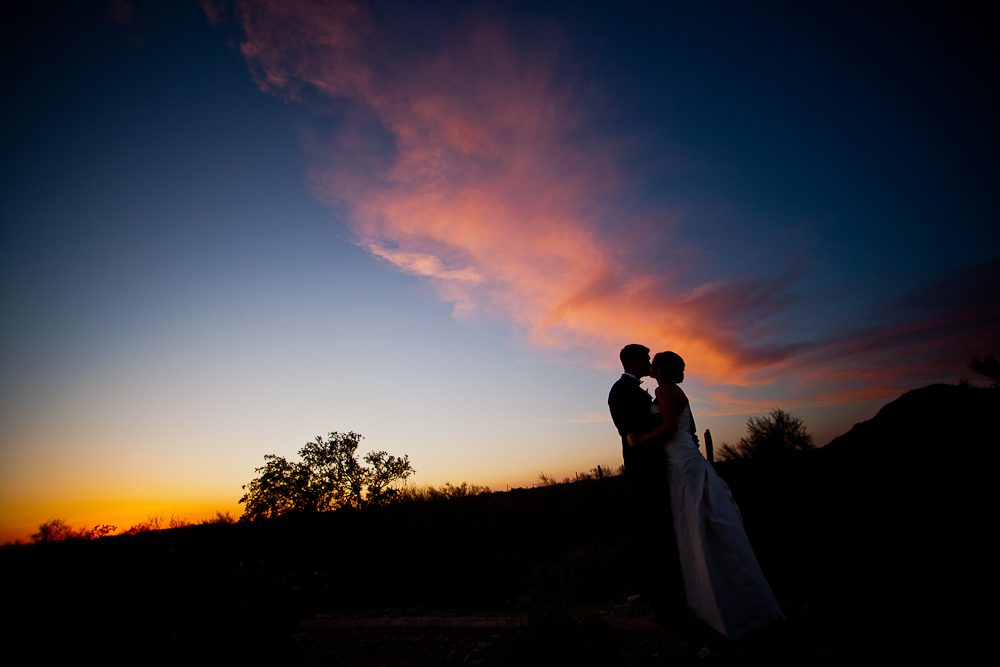 cool shot of wedding couple kissing at sunset