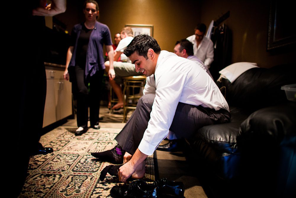 the groom putting his shoes on while getting ready